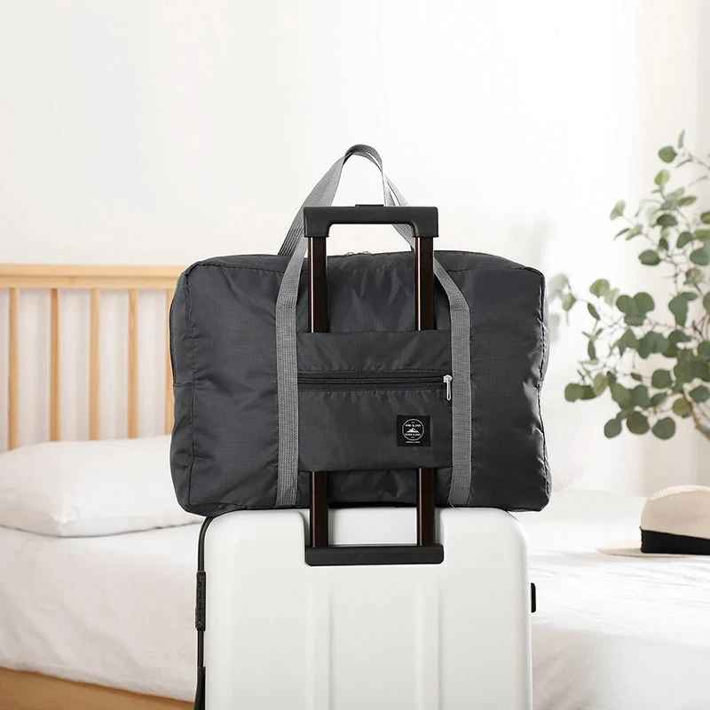 Black foldable travel duffel bag with carry handles and front zip pocket.